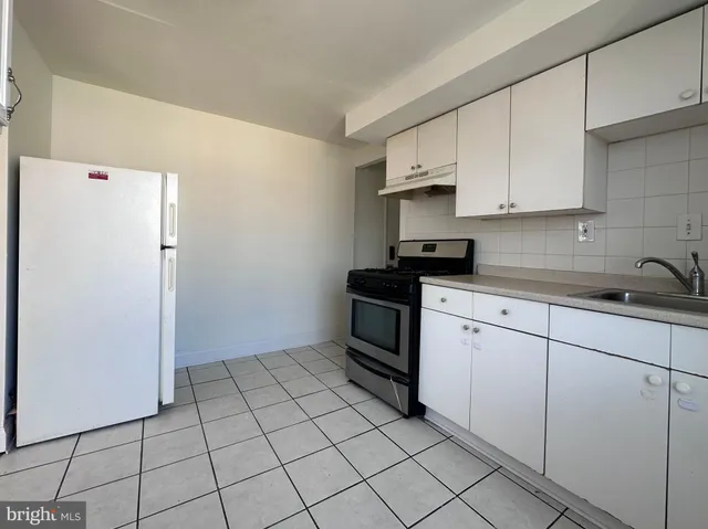 a kitchen with white cabinets a sink and a stove top oven