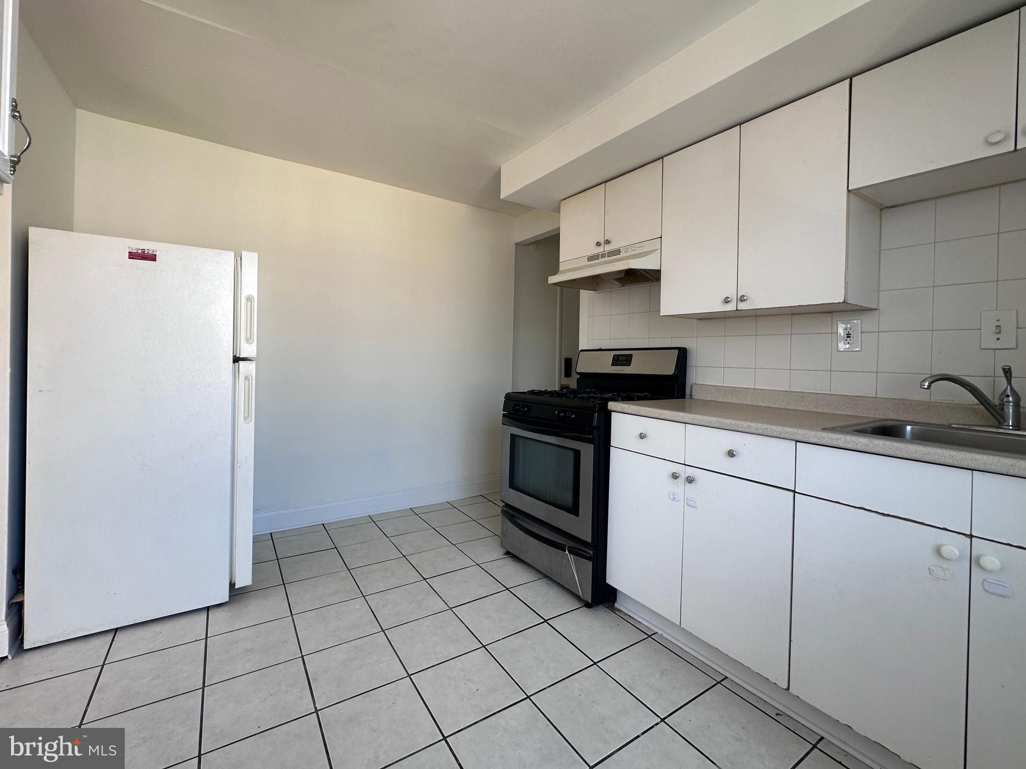 4060 East Roosevelt Boulevard Philadelphia, PA 19124 - Photo 4 of 13 a kitchen with white cabinets a sink and a stove top oven
