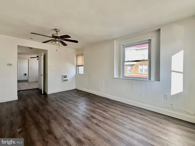 a view of empty room with wooden floor and fan