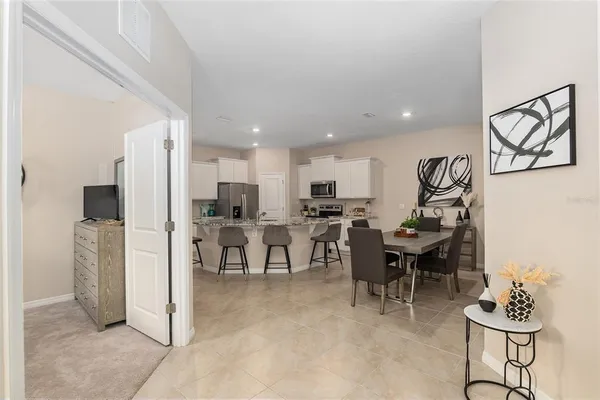 a living room with stainless steel appliances kitchen island a table and chairs in it