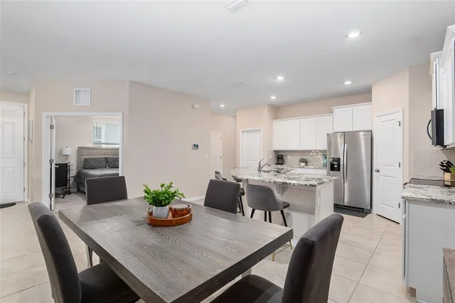 a kitchen with stainless steel appliances granite countertop a stove a sink a microwave a refrigerator and white cabinets with wooden floor