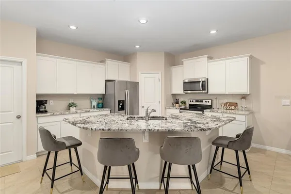 a kitchen with stainless steel appliances kitchen island granite countertop a sink refrigerator and cabinets