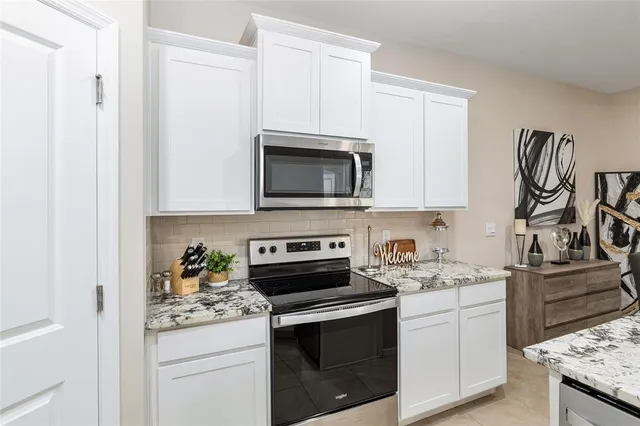 a kitchen with granite countertop a refrigerator a stove a dining table and chairs with wooden floor