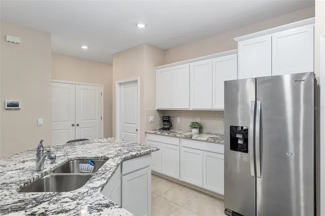 a utility room with granite countertop stainless steel appliances a chimney a sink and a refrigerator