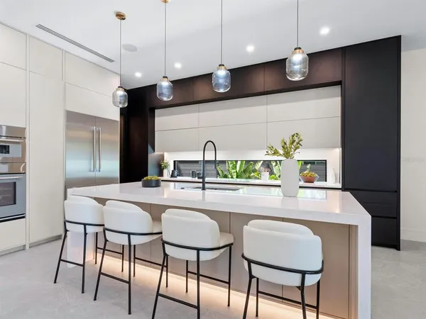 a kitchen with stainless steel appliances kitchen island granite countertop a table chairs and a refrigerator