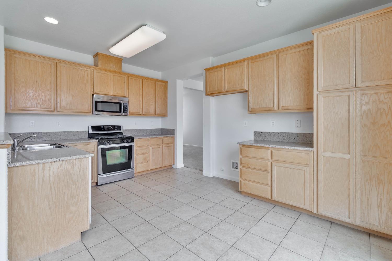863 Chianti Circle Coalinga, CA 93210 - Photo 25 of 35 a kitchen with granite countertop white cabinets and stainless steel appliances