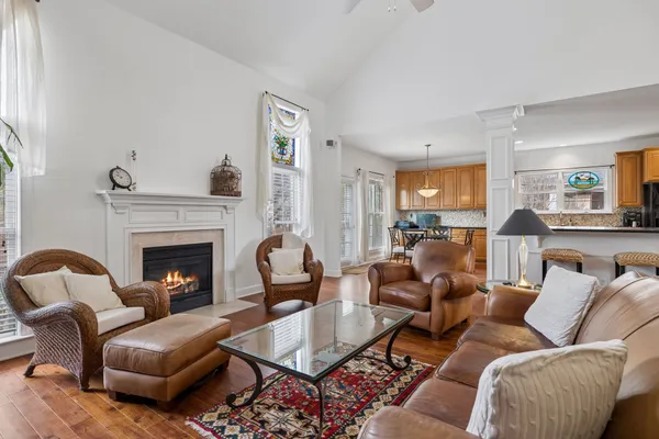 a living room with furniture kitchen view and a wooden floor