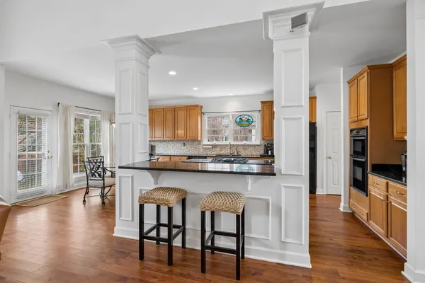 a kitchen with stainless steel appliances kitchen island granite countertop a table chairs sink and cabinets