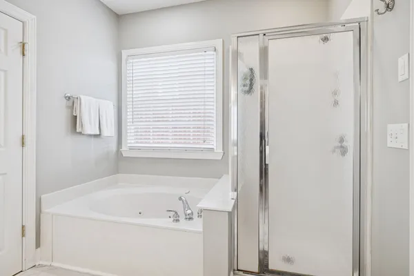 a spacious bedroom with a bed and a flat tv screen on dresser