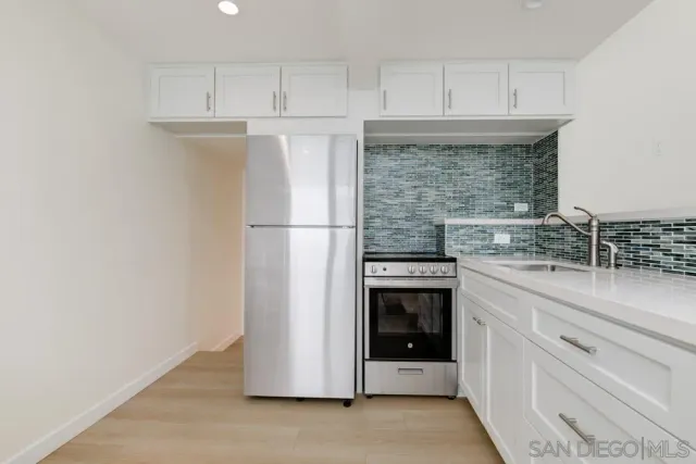 a kitchen with stainless steel appliances kitchen island granite countertop a dining table chairs and a refrigerator