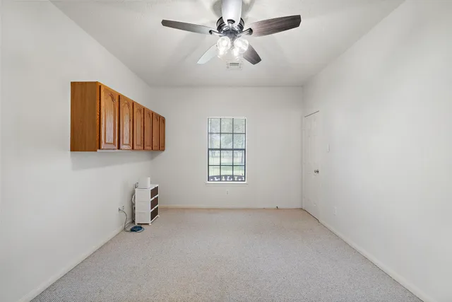 an empty room with windows and fan