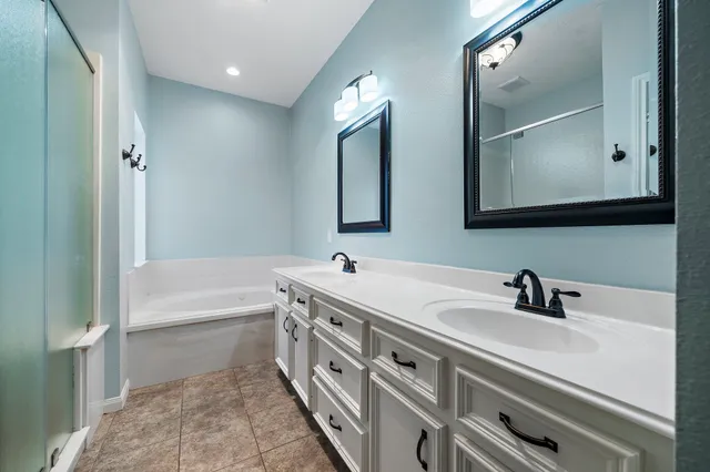 a bathroom with a tub a sink and mirror