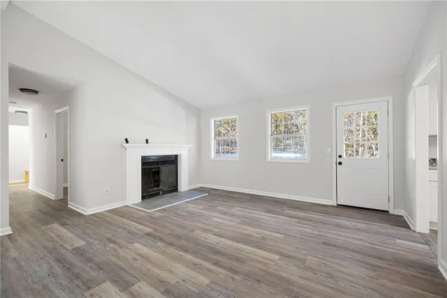 an empty room with windows and fireplace