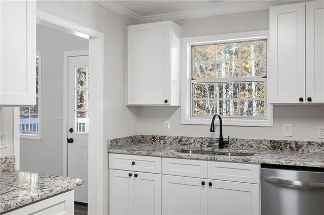 a kitchen with granite countertop white cabinets and window