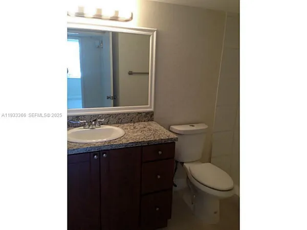 a bathroom with a granite countertop sink and a toilet