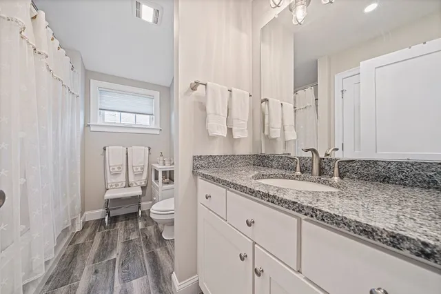 a bathroom with a granite countertop sink and a toilet