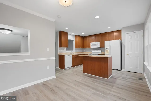a kitchen with stainless steel appliances granite countertop a refrigerator and a wooden floors