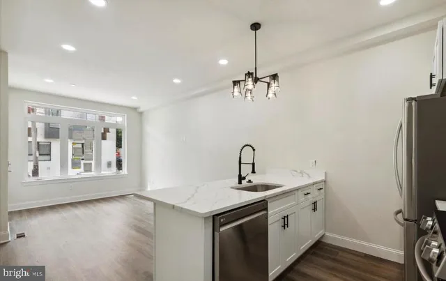 a view of a kitchen with a sink stainless steel appliances and wooden floor