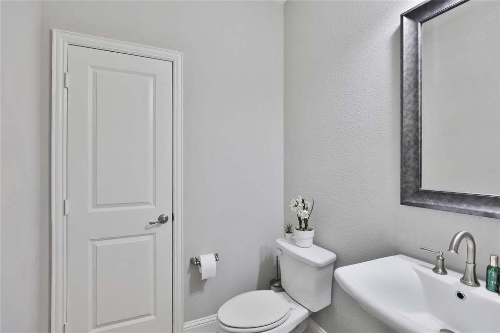 925 Spring Falls Drive McKinney, TX 75071 - Photo 20 of 40 a bathroom with a toilet a sink and mirror