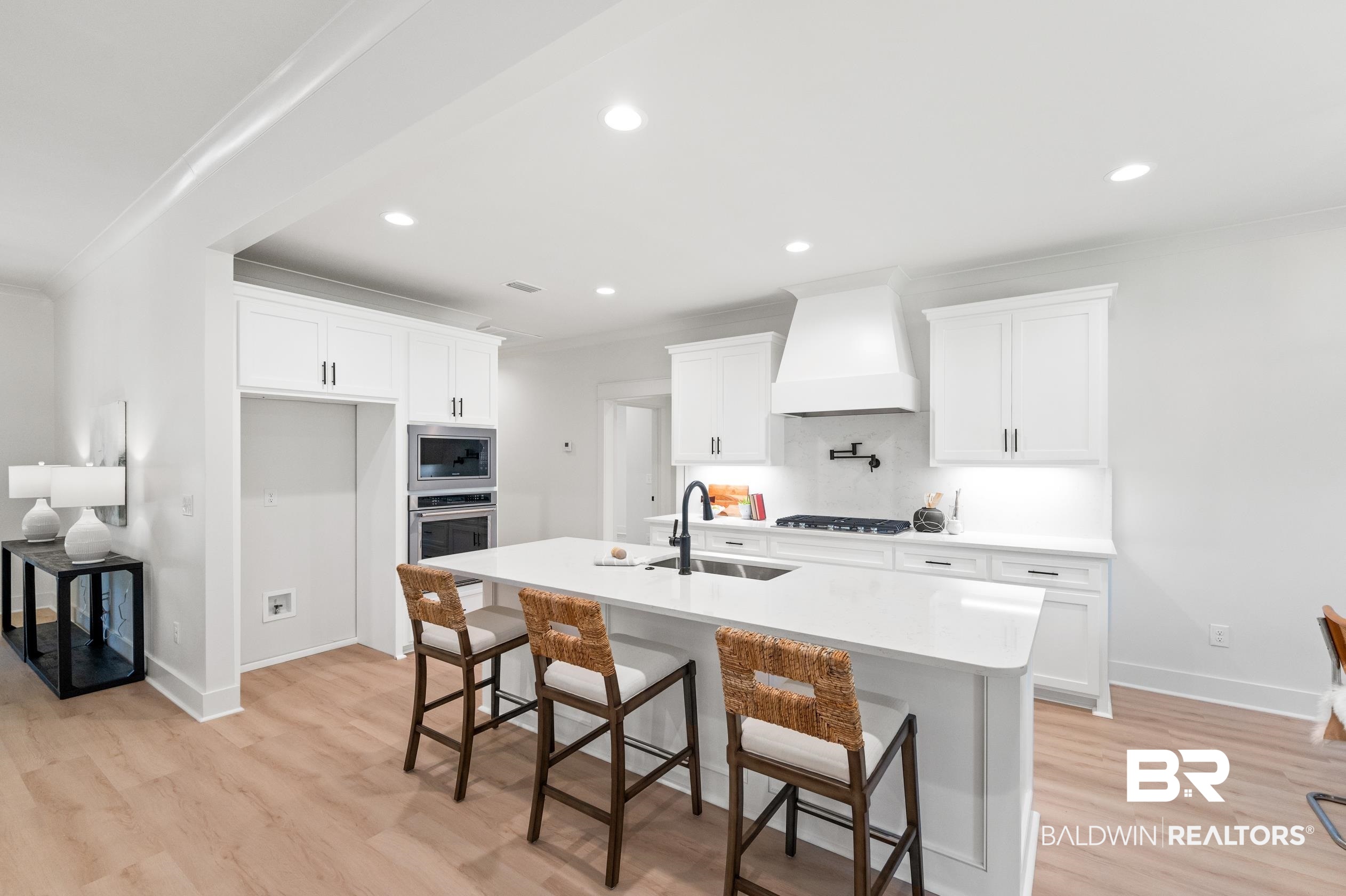 28889 Canal Road Orange Beach, AL 36561 - Photo 9 of 55 Kitchen featuring premium range hood, stainless steel appliances, a kitchen island with sink, sink, and white cabinetry