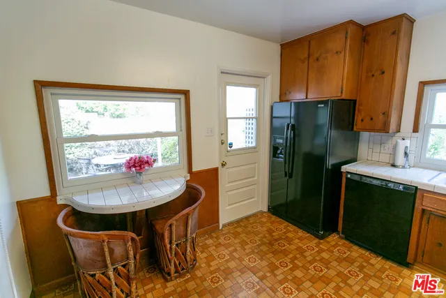 a kitchen with stainless steel appliances granite countertop a refrigerator a sink a stove a dining table and chairs