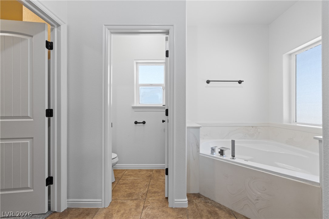 575 Gann Avenue Logandale, NV 89021 - Photo 36 of 75 A deep soaking tub with surrounding white tile provides a tranquil retreat within this spacious bathroom.