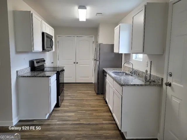 a kitchen with granite countertop a sink stove and refrigerator