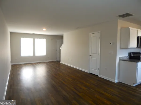 an empty room with wooden floor and windows