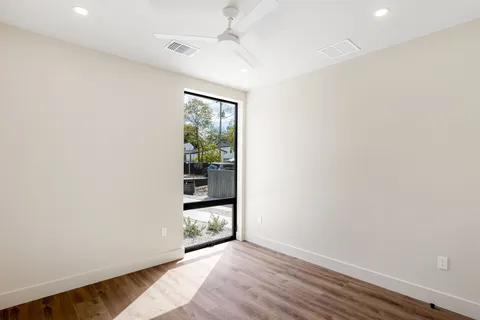 an empty room with wooden floor and windows