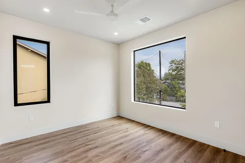 an empty room with wooden floor and windows