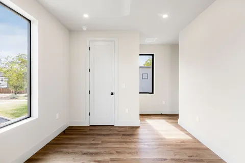 an empty room with wooden floor and windows