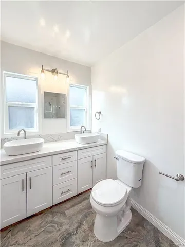 a bathroom with a toilet a sink a mirror and a window