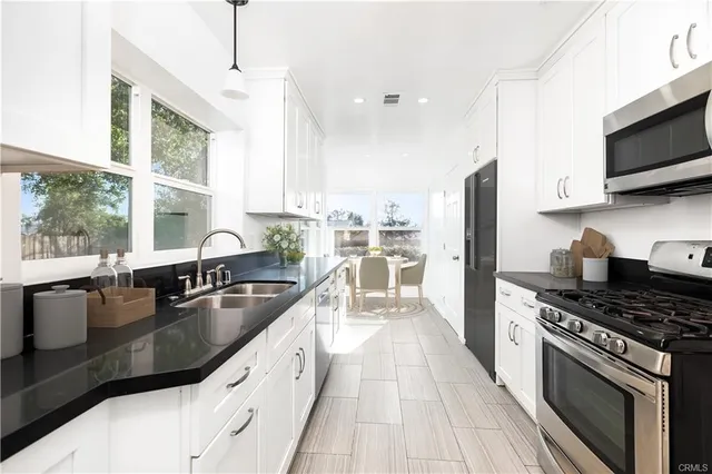 a kitchen with stainless steel appliances granite countertop a sink a stove and a refrigerator