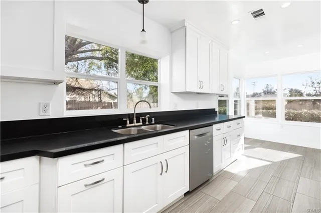 a kitchen with granite countertop white cabinets white appliances a sink and a large window