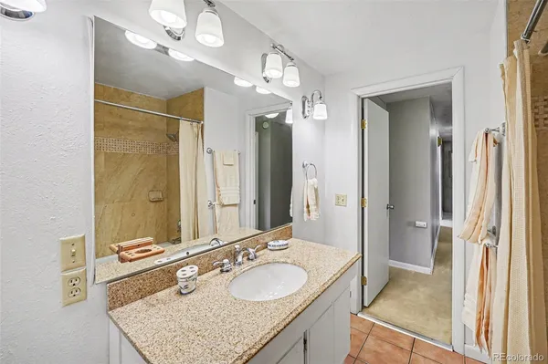 a bathroom with a granite countertop double vanity sink mirror and shower