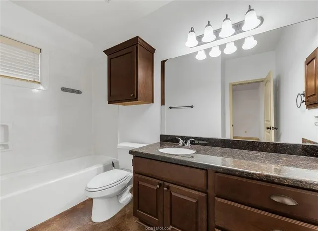 a bathroom with a granite countertop sink a toilet and a large mirror
