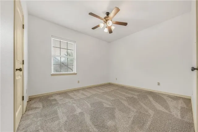 an empty room with windows and ceiling fan