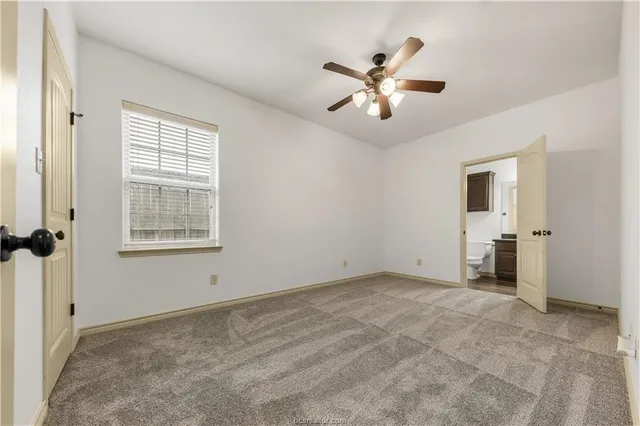 a view of an empty room with chandelier fan and fire place