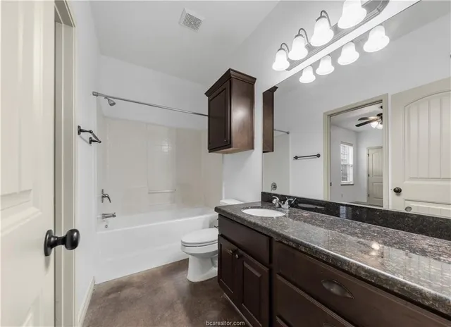 a bathroom with a granite countertop sink a large mirror and a bathtub