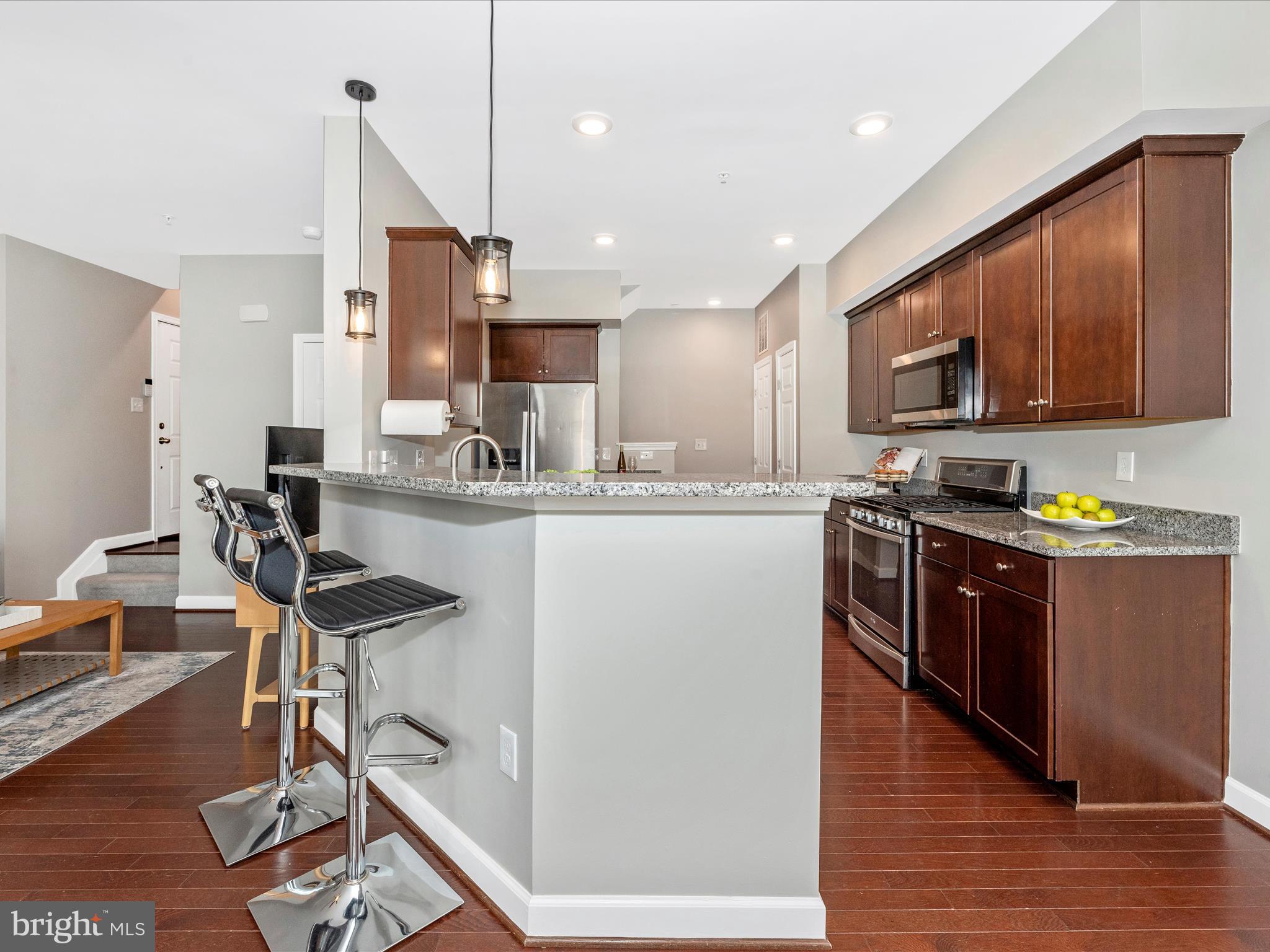 5920 Forum Square Frederick, MD 21703 - Photo 11 of 56 a kitchen with kitchen island granite countertop wooden floors stainless steel appliances a sink and a living room view