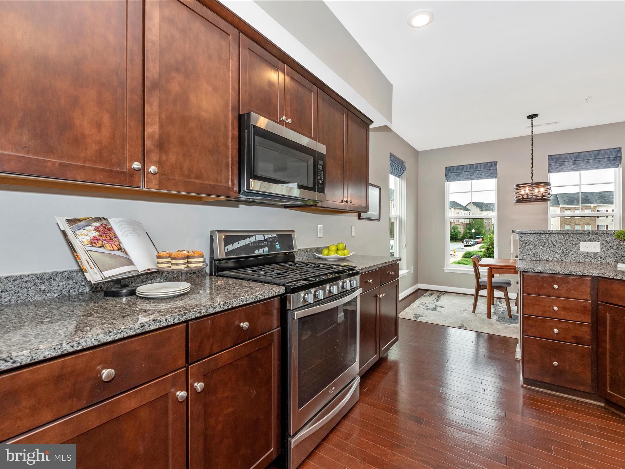 5920 Forum Square Frederick, MD 21703 - Photo 17 of 56 a kitchen with stainless steel appliances granite countertop a stove top oven a sink dishwasher a dining table and chairs with wooden floor