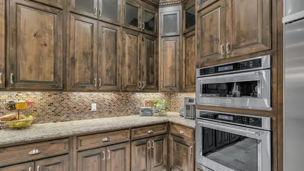 a kitchen with stainless steel appliances kitchen island granite countertop a table chairs and a view of living room