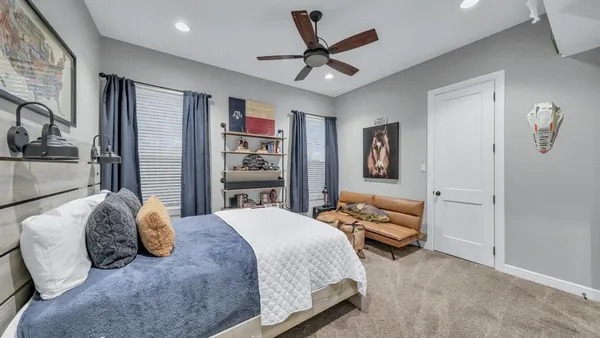 a bedroom with a bed couch and a ceiling fan