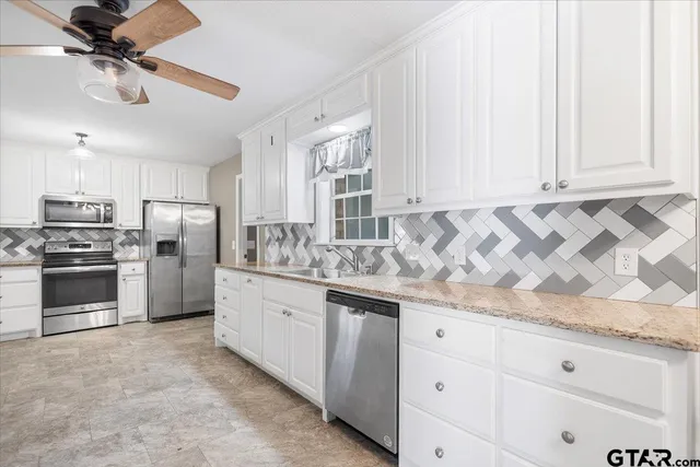 a kitchen with granite countertop white cabinets and stainless steel appliances