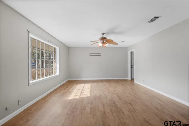 a view of an empty room with wooden floor and a window
