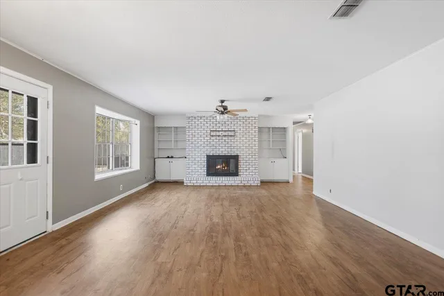 a view of an empty room with a fireplace and a window