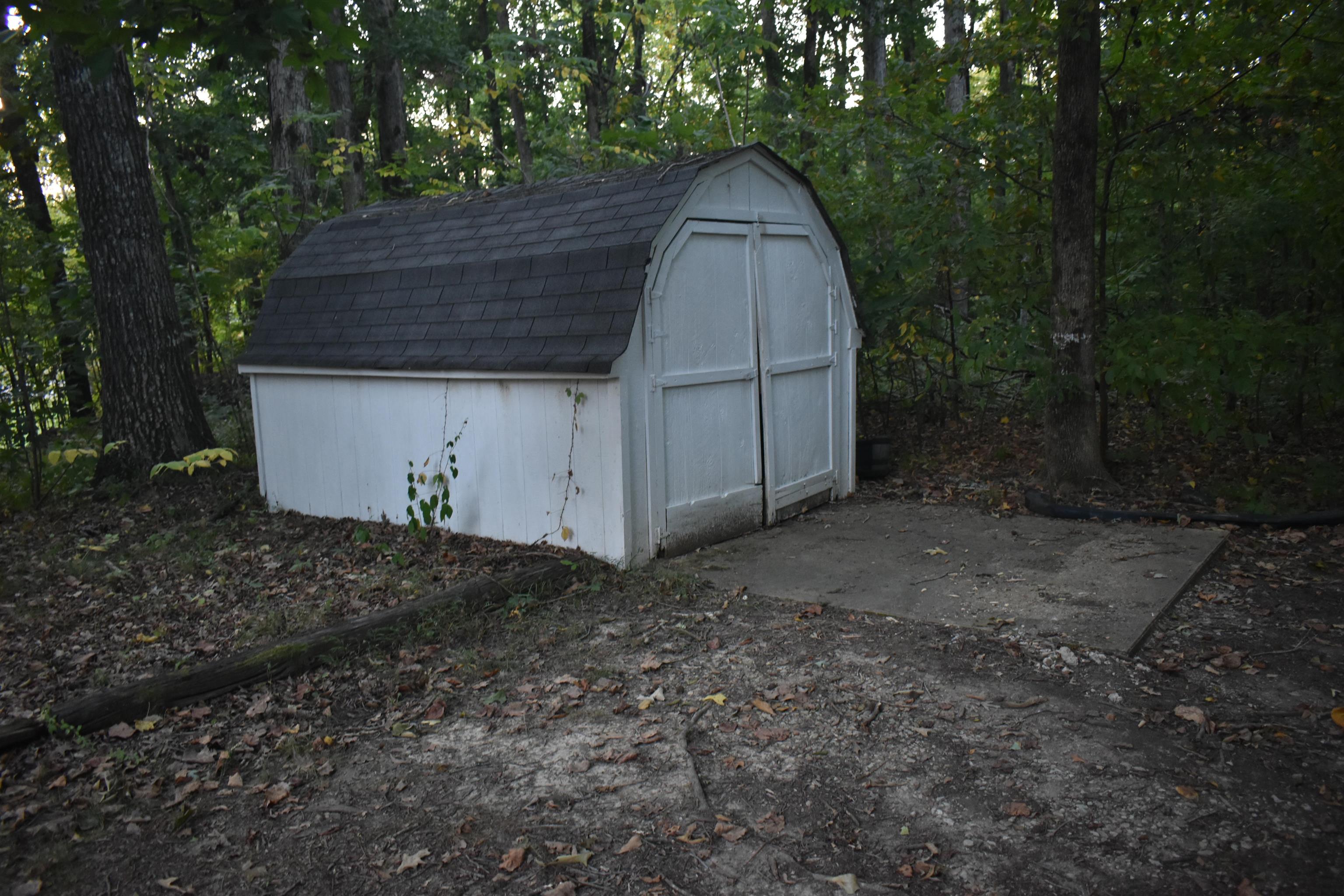 82 Ester Lane Ramer, TN 38367 - Photo 31 of 40 Detached storage shed with a gambrel roof and double doors, set on a concrete pad
