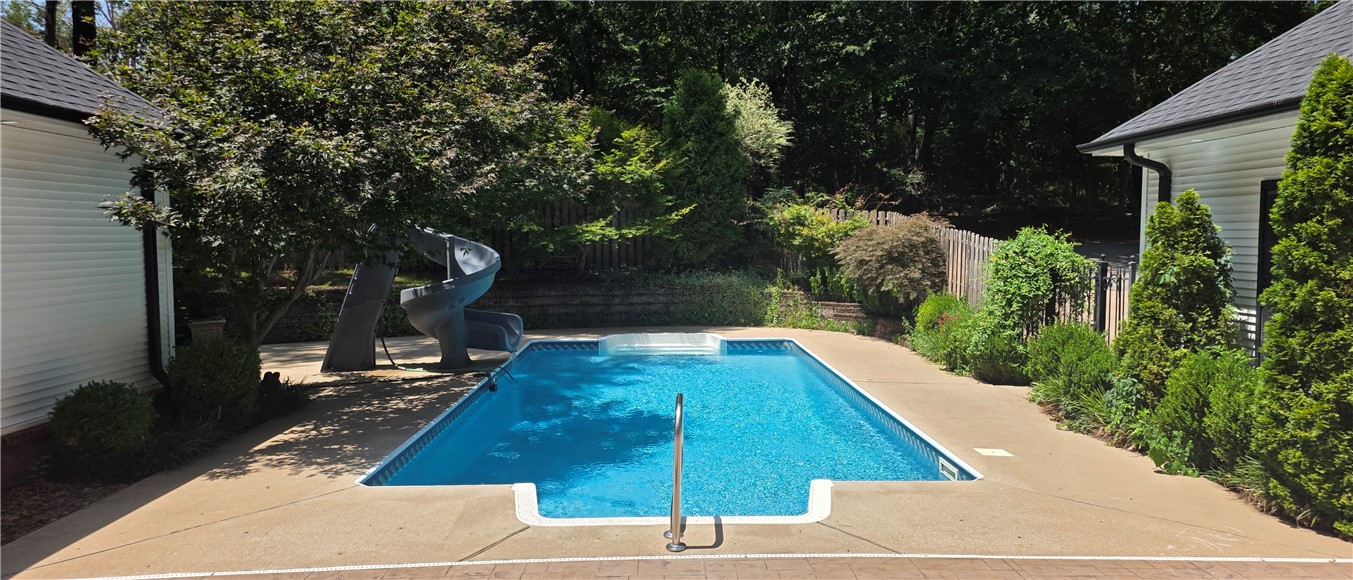 19489 Oak Circle Springdale, AR 72764 - Photo 53 of 58 Rectangular inground pool featuring a built-in slide, concrete decking, and surrounding mature landscaping