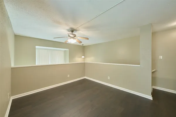 an empty room with wooden floor and ceiling fan