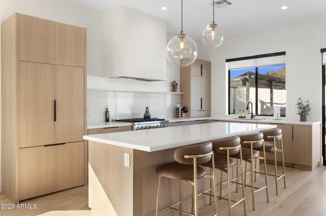 a kitchen with stainless steel appliances granite countertop a island a stove a refrigerator a sink a dining table and chairs with wooden floor